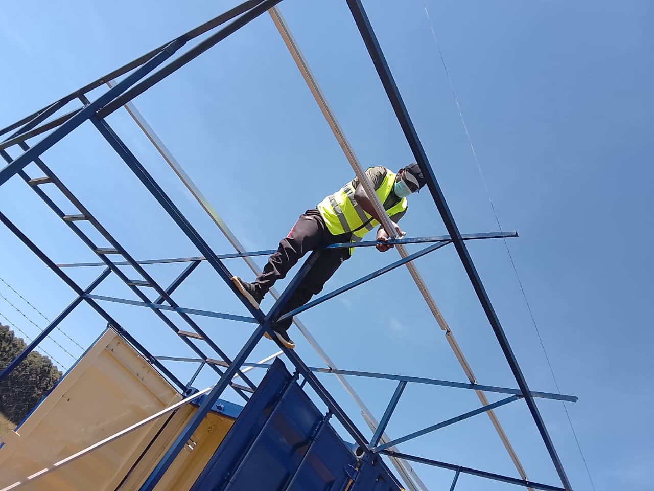 AFENERGY fabricator assembling a steel canopy frame above a container