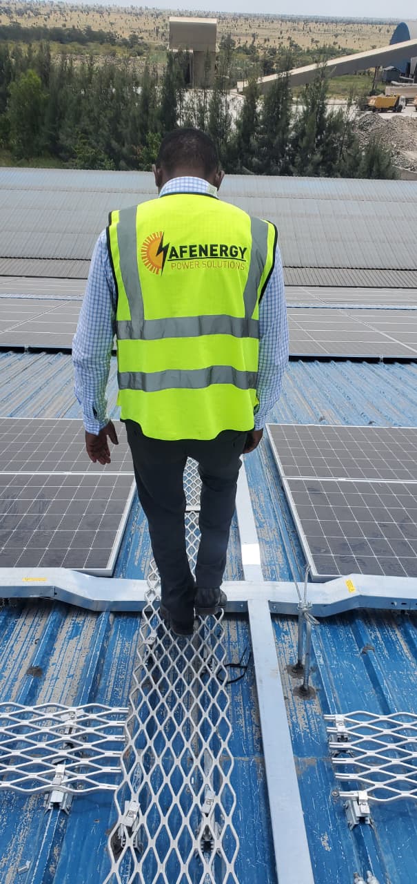 AFENERGY site engineer in branded PPE inspecting an industrial rooftop solar PV array in Kenya